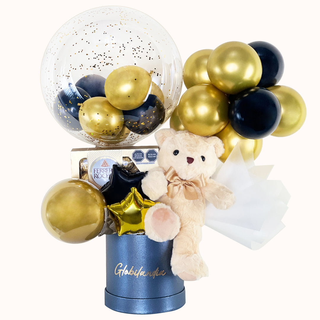 Gift box en colores dorado y negro, ideal para cumpleaños o cualquier ocasión especial, que incluye 1 peluche de osito mediano, 1 globo burbuja personalizable, 1 caja de Ferrero Rocher (8 unidades), globitos decorativos y caja de regalo deluxe satinada, perfecto para sorprender con un detalle especial.