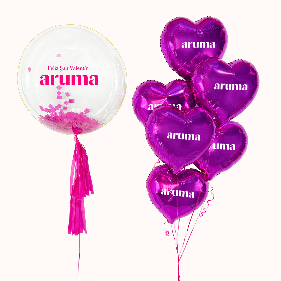 Arreglo de globos corporativo: Bouquet de 1 globo burbuja con papel seda en su interior, decorada con 2 flequillos de papel personalizado con logo,  6 globos metálicos en forma de corazón color fucsia. personalizados con logo. Para campañas de San Valentín.