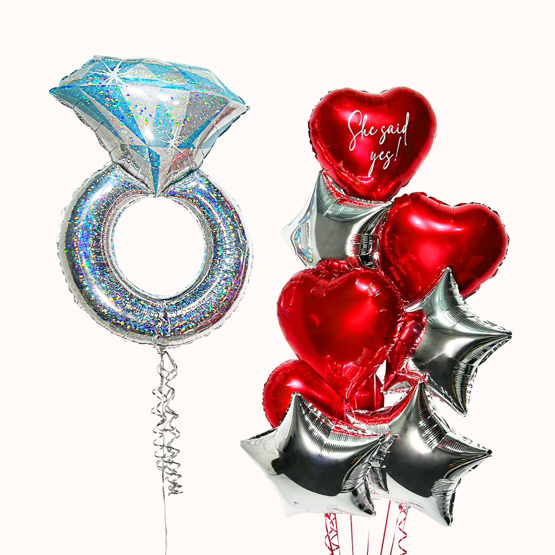 Bouquet de globos con anillo de compromiso en color plata y bouquet compuesto por 3 globos metálicos en forma de corazón rojo y 4 globos metálicos en forma de estrella. Para pedida de mano, compromiso, amor y San Valentín.