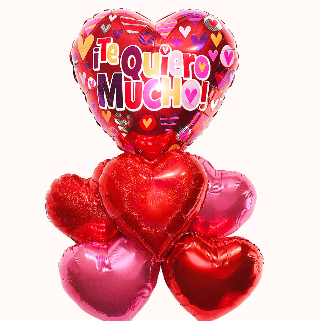 Bouquet de globos metálicos. Globo principal en forma de corazón grande con el mensaje 'Te quiero mucho', acompañado de 5 globos en forma de corazón en tonos rosado y rojo. Detalle para regalo de San Valentín o cualquier ocasión romántica.