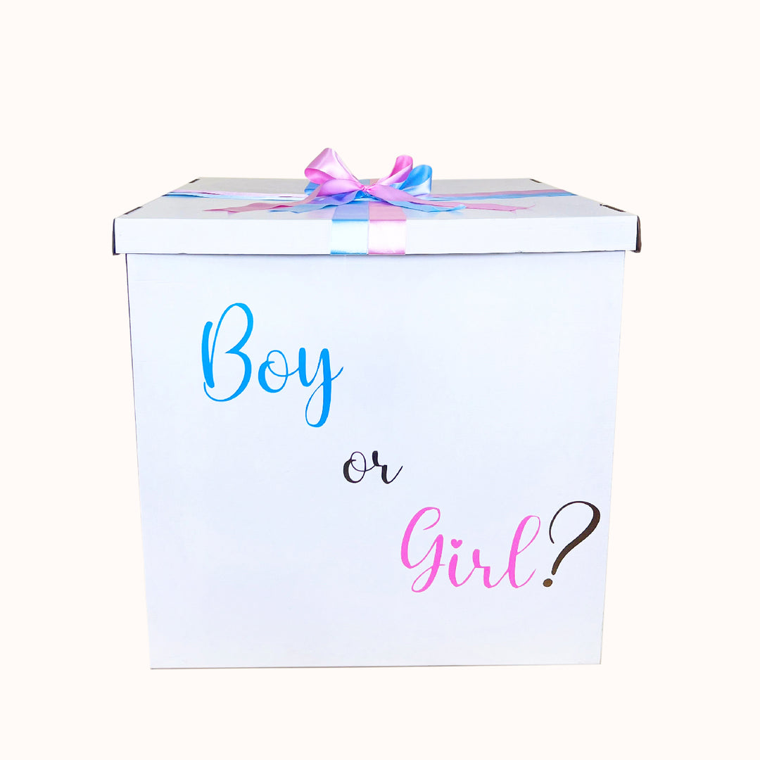 Caja Gender Reveal vacía en color blanco, decorada con cinta de tela en tonos rosado y celeste, y personalizada con la frase “Boy or Girl” en celeste y rosado. Medida: 70 cm × 70 cm.