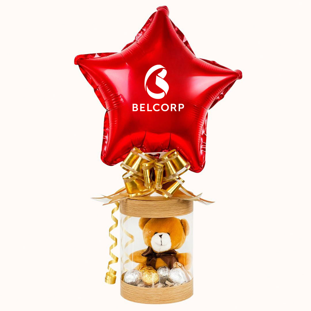 Detalle empresarial de San Valentín: caja de regalo transparente con osito y chocolates, con globo logo empresa. Para campaña corporativa de San Valentín. Para obsequio a clientes y colaboradores.