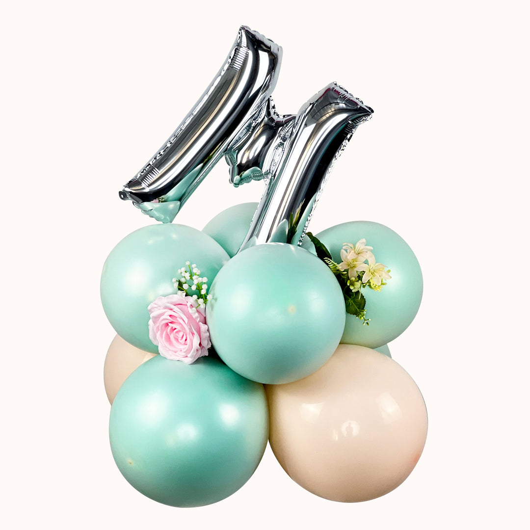 Base de globos decorado con la letra M y flores Artificiales para regalar a Mamá en su día.