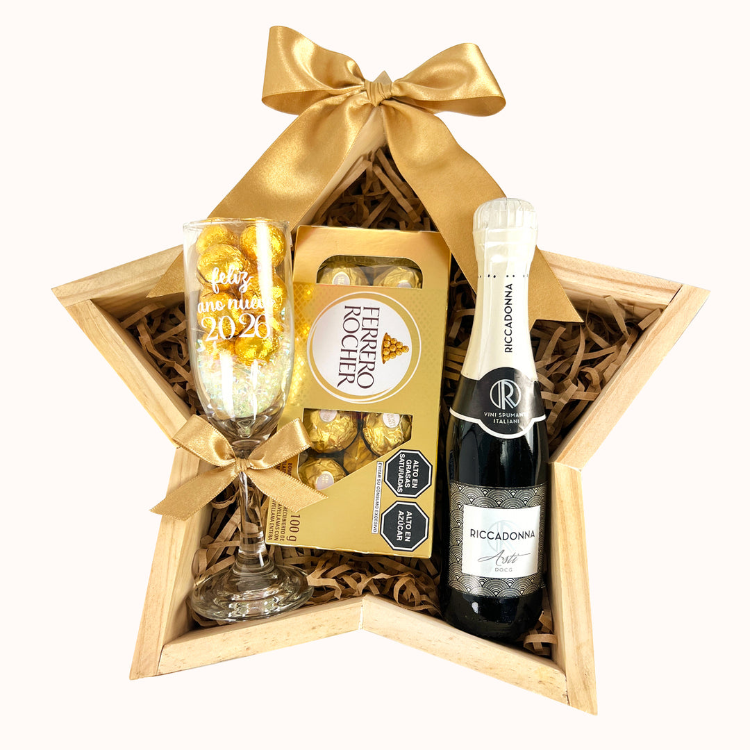 Hermoso Gift Box sobre base de pino con forma de estrella. Incluye 1 botella de Ricadonna Asti, 1 caja de chocolates Ferrero Rocher de 8 unidades y una copa de vidrio llena de chocolates. Ideal para celebrar el Año Nuevo con un detalle elegante y especial.