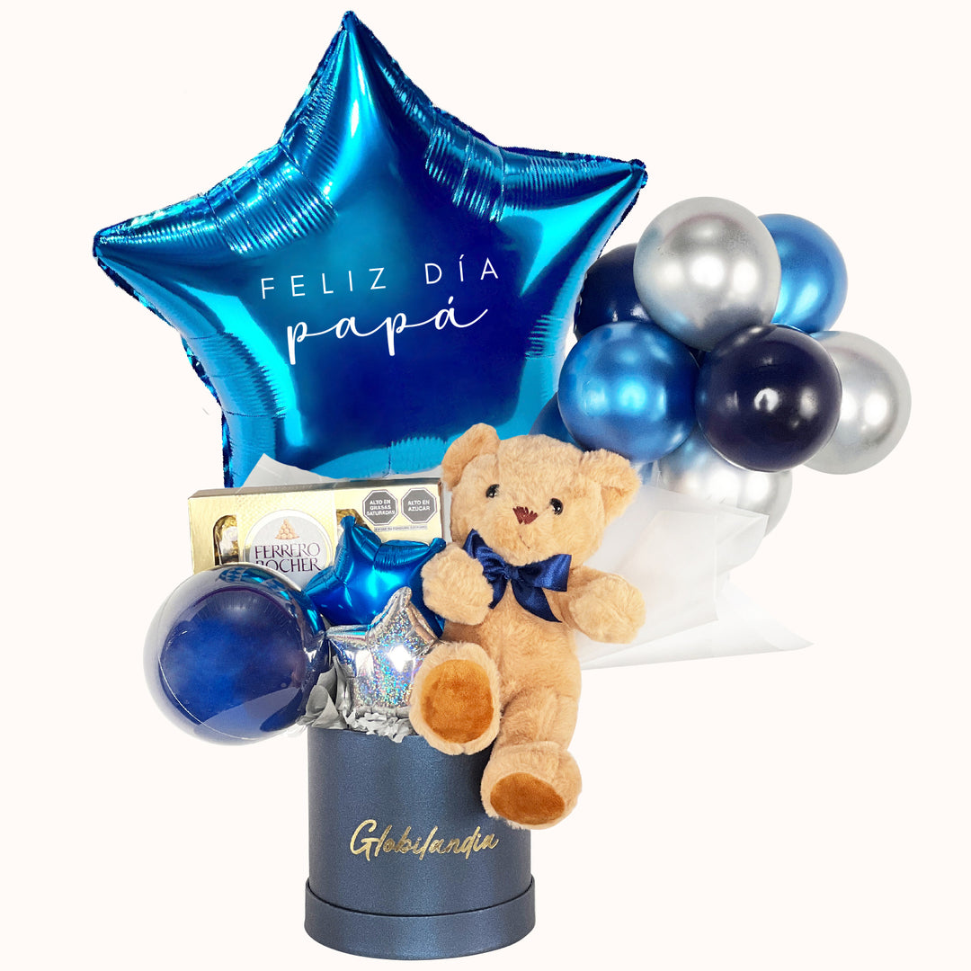 Caja de regalos para sorprender a papá en el Día del Padre. Incluye un oso de peluche, deliciosos chocolates y un globo personalizado con la frase “El mejor papá del mundo”, en elegantes tonos plata y azul. Un detalle perfecto para papi.