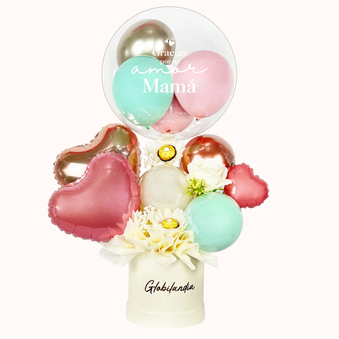 Regalo o detalle en caja satinada, decorada con globos y globo burbuja personalizado, incluye 3 unidades de chocolate Ferrero Rocher y globos en forma de corazón. Ideal para obsequiar a mamá en su día.