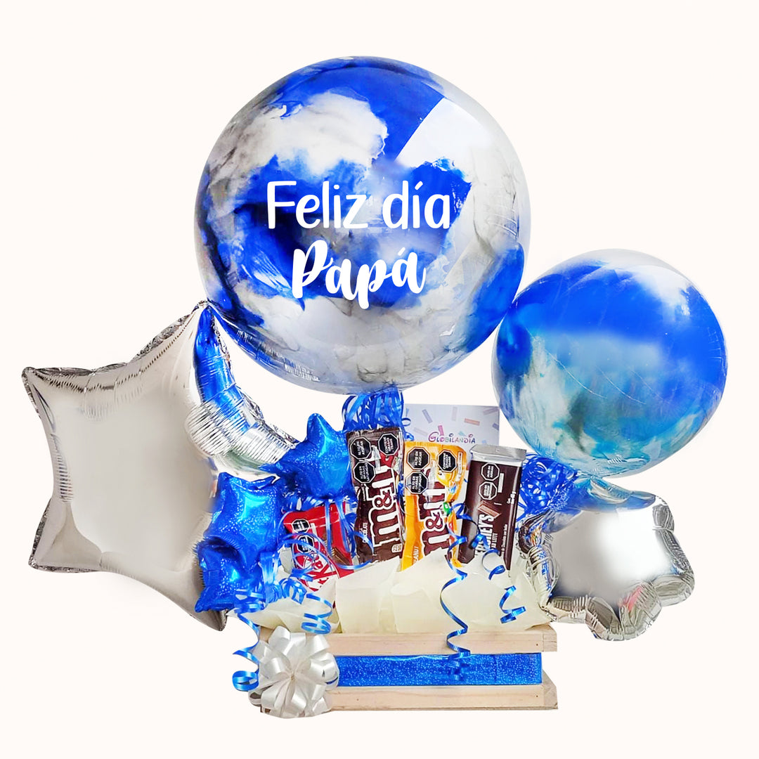 Gift box especial que incluye 1 globo burbuja pintado y personalizado en 2 colores, 1 globo burbuja pintado mediano en 2 colores, varios globos estrella, globitos decorativos pequeños, 4 chocolates importados y caja pino mediana; una opción ideal para sorprender y engreír a papá en su día especial.