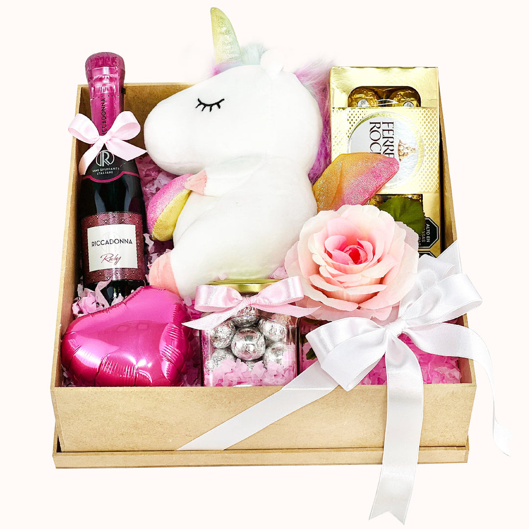 Arreglo de regalo que incluye rosas decorativas artificiales, 1 peluche unicornio pequeño, 1 caja de Ferrero Rocher (8 unidades), globito corazón decorativo, 1 jar de chocolates, 1 botella de Riccadonna Ruby de 200 ml y caja de regalo cuadrada. Ideal para sorprender en distintas ocasiones.