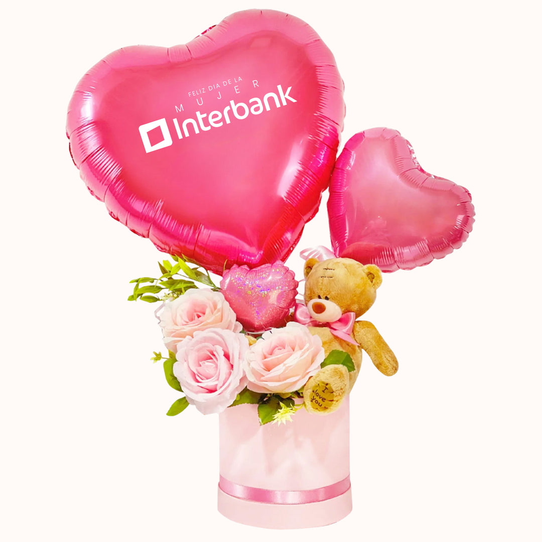 Arreglo corporativo para la campaña del Día de la Mujer que incluye rosas decorativas artificiales, 1 peluche de osito mediano, 1 globo de corazón personalizable con logo y caja de regalo satinada, ideal para obsequios empresariales. 