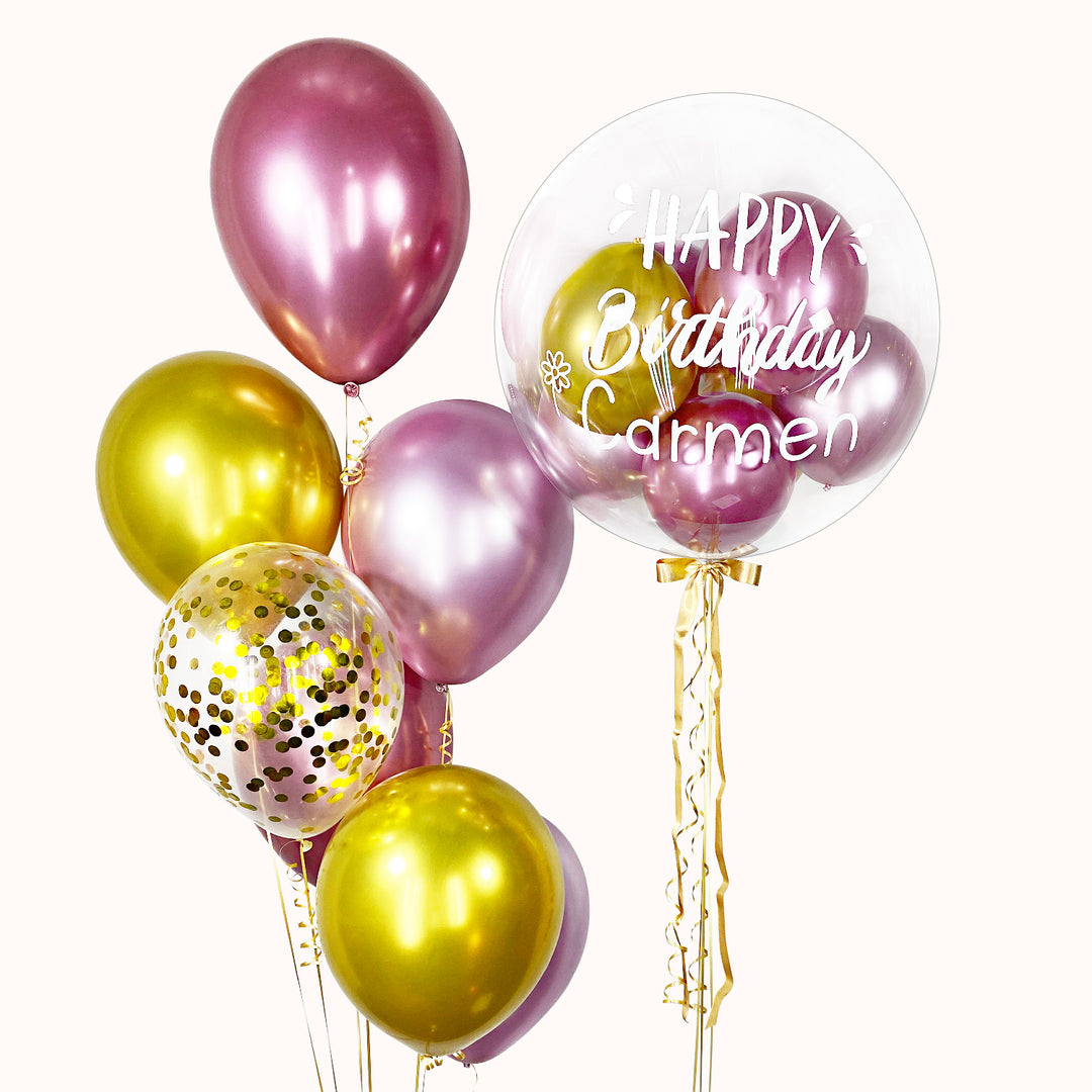 Bouquet  rosado y dorado de 8 globos con helio: 1 globo burbuja con globitos en su interior, 6 globos de látex cromados y 1 globo de látex con confeti. Ideal para celebrar cumpleaños o cualquier ocasión especial.
