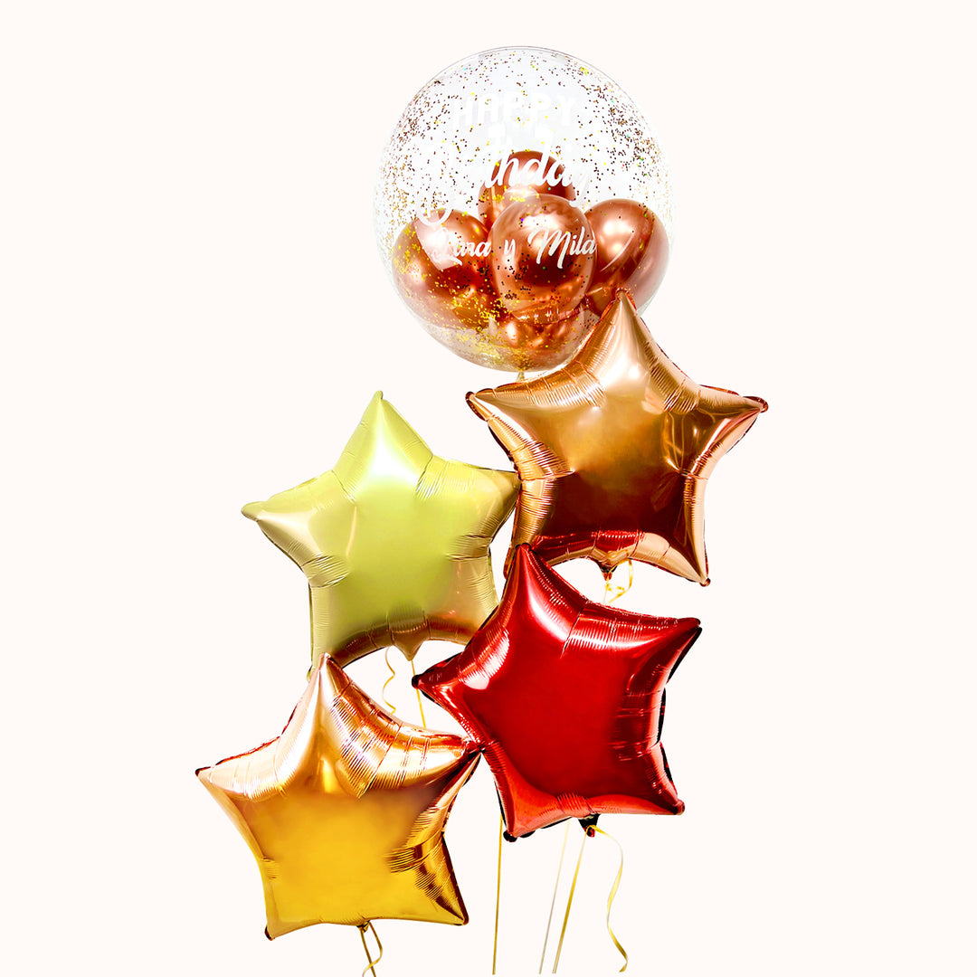 Bouquet de 5 globos con helio: 1 globo burbuja con globos en su interior y escarcha, y 4 globos estrella metálicos. Color a elección. Ideal para celebrar cumpleaños o cualquier ocasión especial.