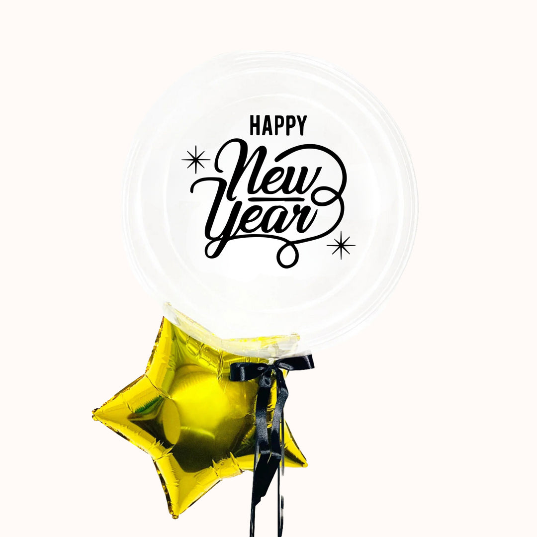 Bouquet globo burbuja personalizado “Happy New Year”, una estrella dorada metálica y un lazo de tela negro. Ideal para decorar y celebrar Año Nuevo.
