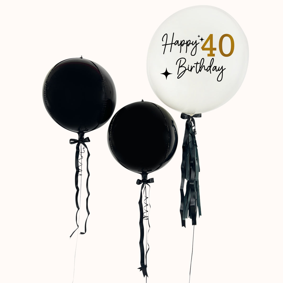 Pack de 3 globos: 1 globo burbuja con globo en su interior blanco. Personalizable y 2 esferas metálicas en color negro, decoradas con flequillos y lazos. Ideal para festejar cumpleaños, aniversarios o cualquier ocasión especial. Inflados con helio 100% puro.