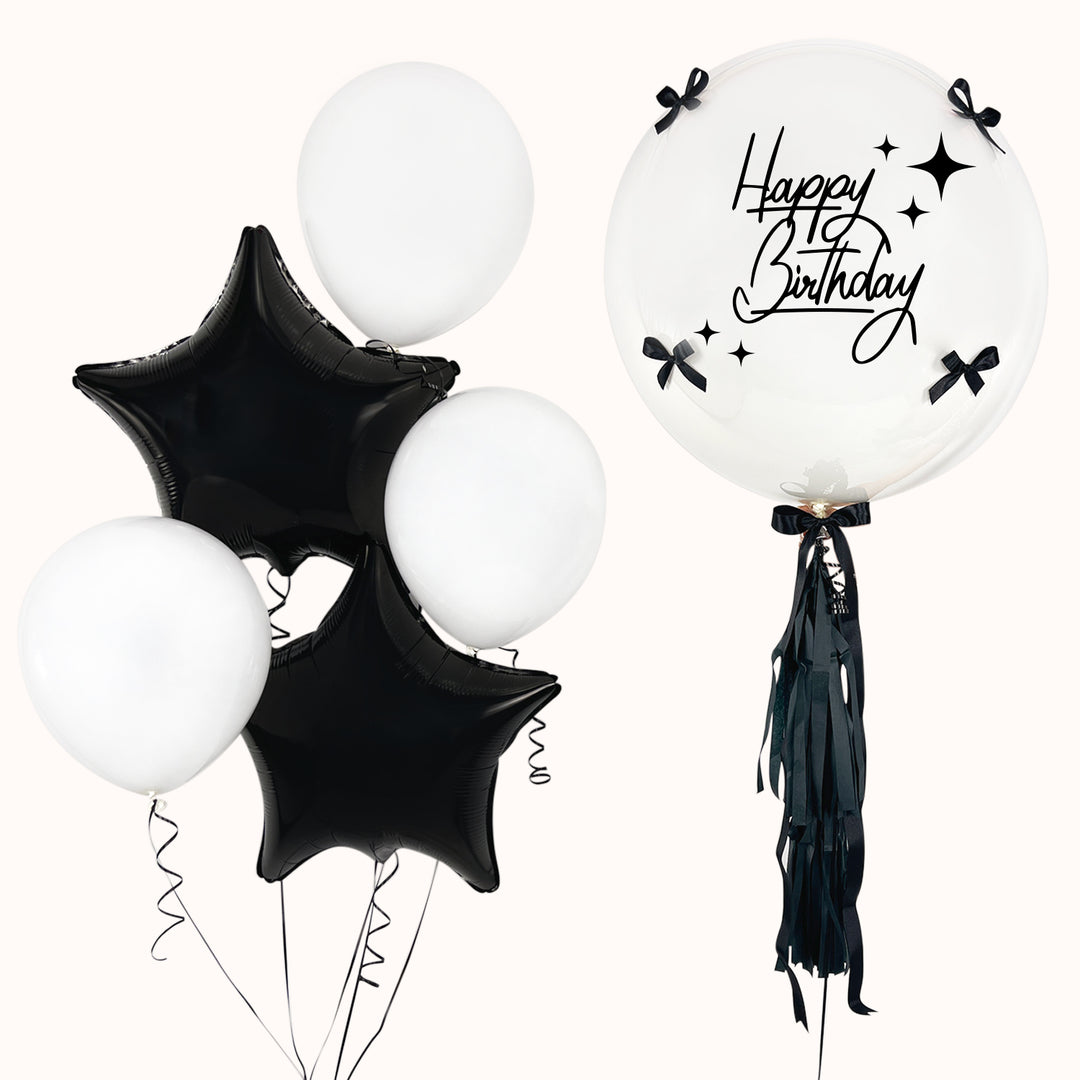 Ramo de 6 globos con helio: 1 globo burbuja con globo en su interior, decorado con lazos y flequillos; 3 globos de látex y 2 globos en forma de estrella. Arreglo en color blanco y negro. Ideal para cumpleaños o cualquier ocasión especial.