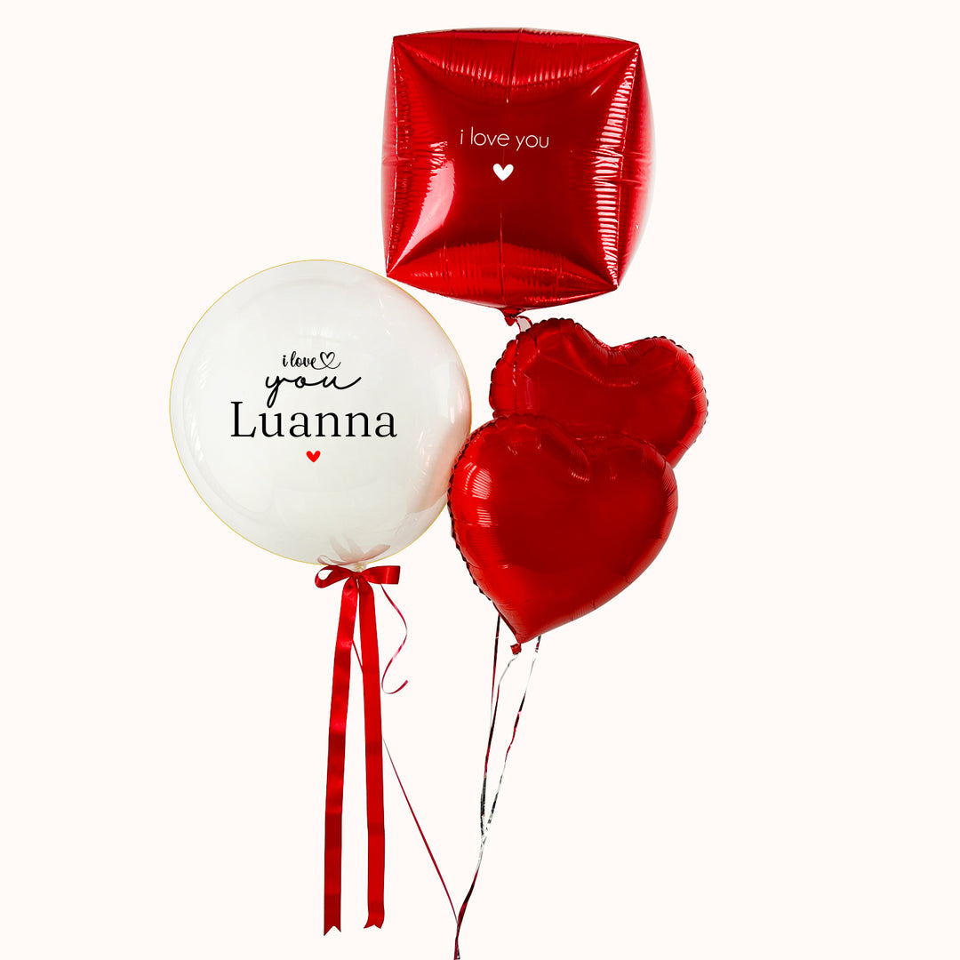 Bouquet de globos en tonos blanco y rojo. Incluye un globo burbuja con globo interno personalizado, acompañado de globos metálicos en forma de corazón y cubo. Regalo para San Valentín o cualquier ocasión especial de amor. Inflado con helio 100% puro.