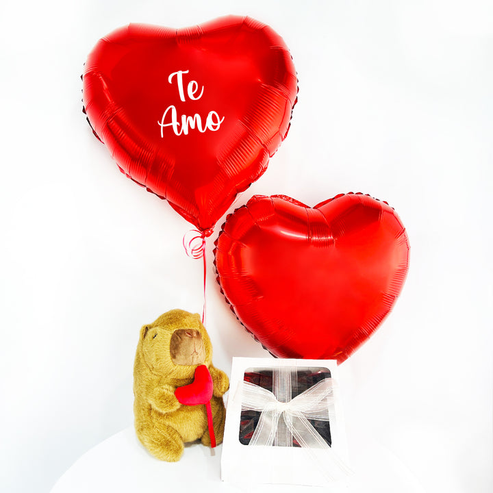 Arreglo, regalo que incluye 1 peluche de capibara chico, 2 globos de corazón inflados con helio, 1 caja mini de dulces y personalización en uno de los corazones. Pedidos con 1 día de anticipación.