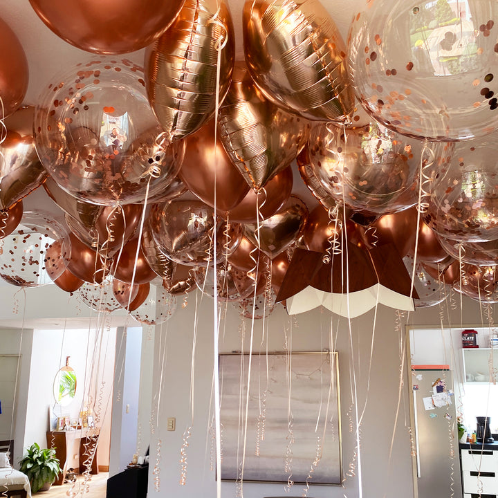 Conjunto de globos burbuja, metálicos y de látex inflados con helio flotando en el techo con cintas de agua decorativas