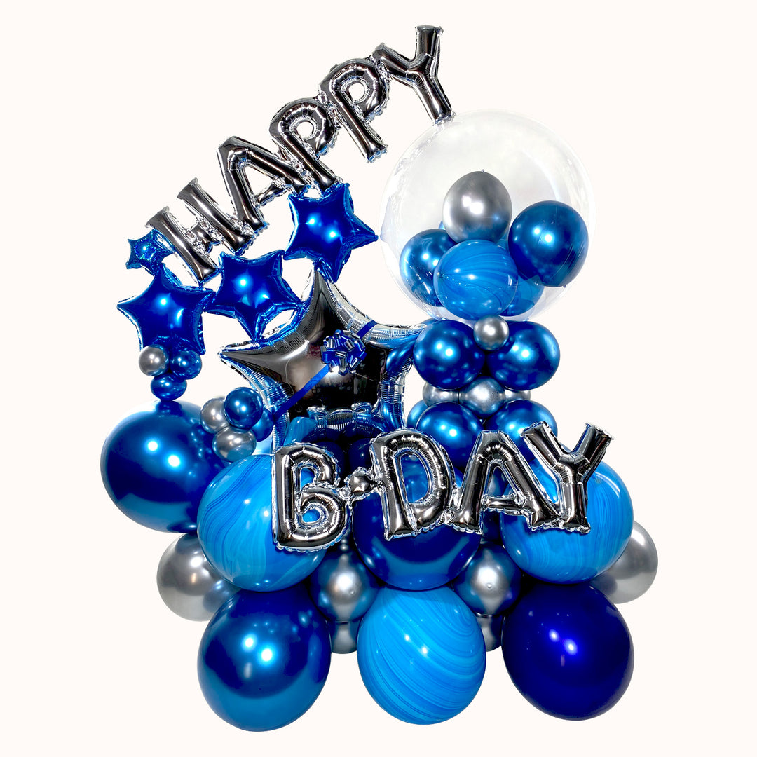 Mural azul y plata con base de globos de látex, decorado con globo burbuja personalizado con globitos en su interior y globos de letras Happy Birthday plateados, ideal para cumpleaños.