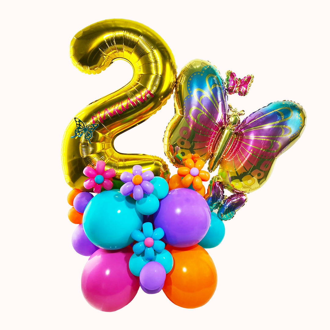 Mural con base de globos de látex, 1 globo metálico de número dorado y 1 globo metálico en forma de mariposa.  en color fucsia y turquesa. Ideal para decorar o regalar en cumpleaños.
