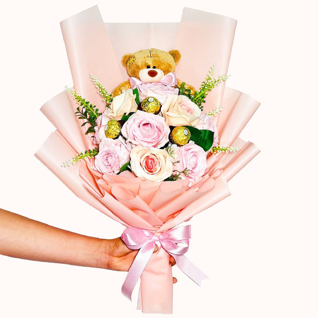 Arreglo, ramo de rosas artificiales con oso de peluche y 3 unidades de chocolate Ferrero Rocher, envuelto delicadamente en papel coreano en tonos salmón y rosado. Un regalo especial para San Valentín, o cualquier ocasión especial